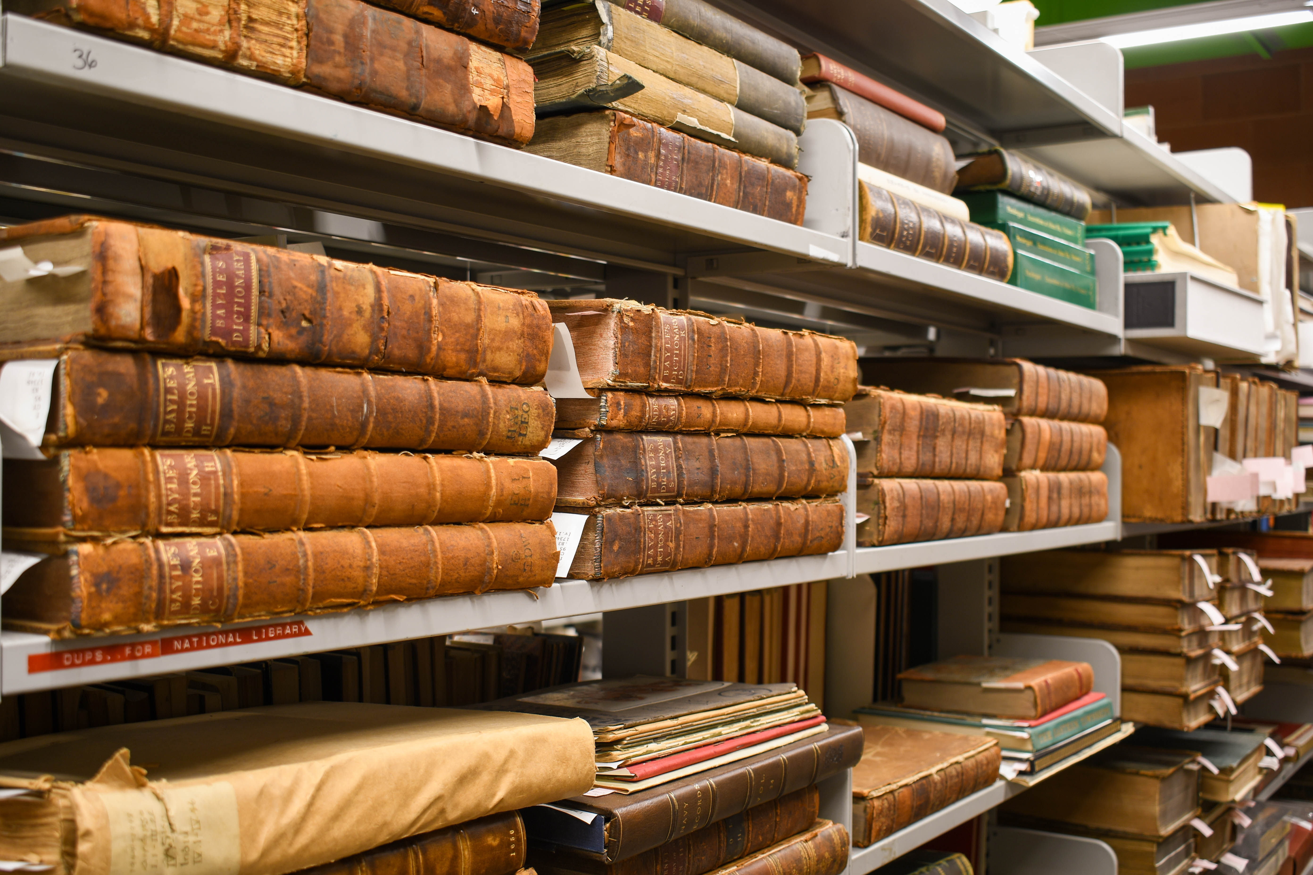 Colour photograph of old leather bound books laying on shelves